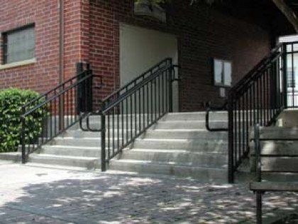 A set of stairs leading up to a brick building with a metal railing.
