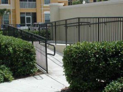 A handicapped ramp is surrounded by bushes and a fence.