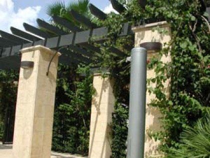 A pergola is surrounded by pillars and trees in a park.