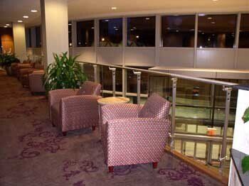 A lobby with chairs and tables and a balcony