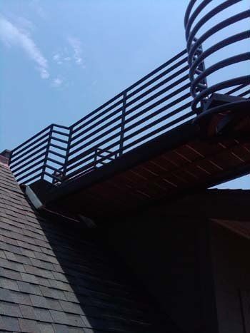 A balcony on the side of a building with a blue sky in the background.