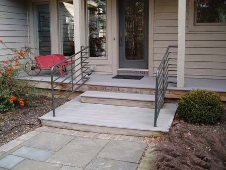 The front porch of a house with a metal railing and steps