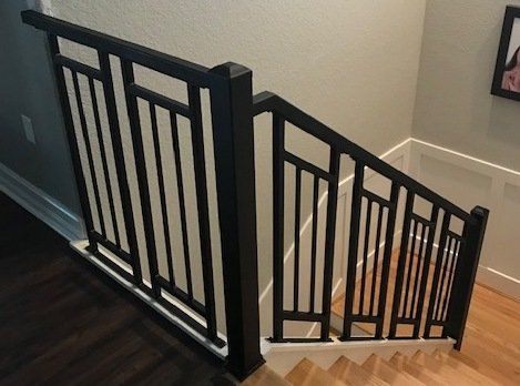 A staircase with a black railing and a picture on the wall.