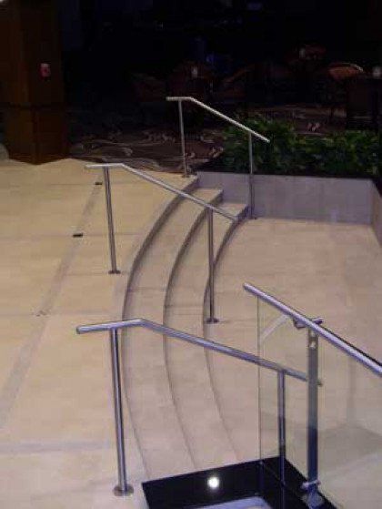 A set of curved stairs with a stainless steel railing