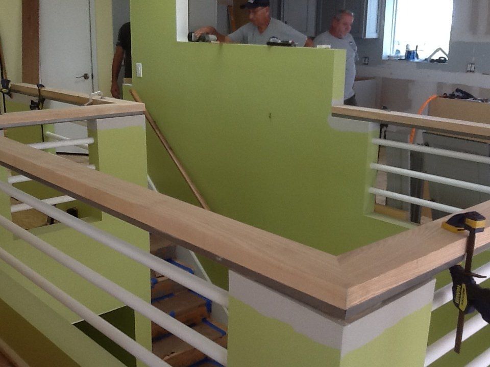 Two men are working on a staircase with a wooden railing