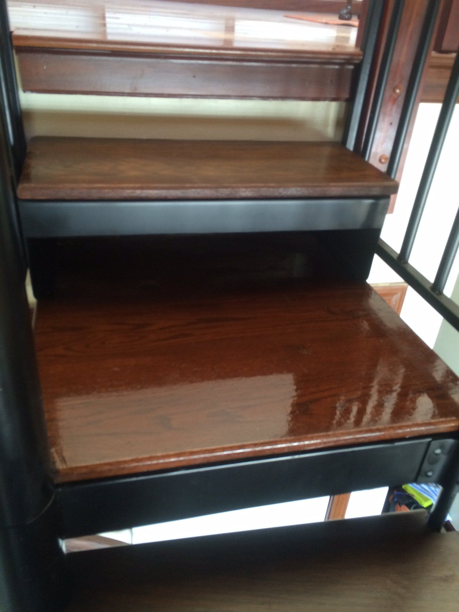 A close up of a wooden staircase with a black railing.