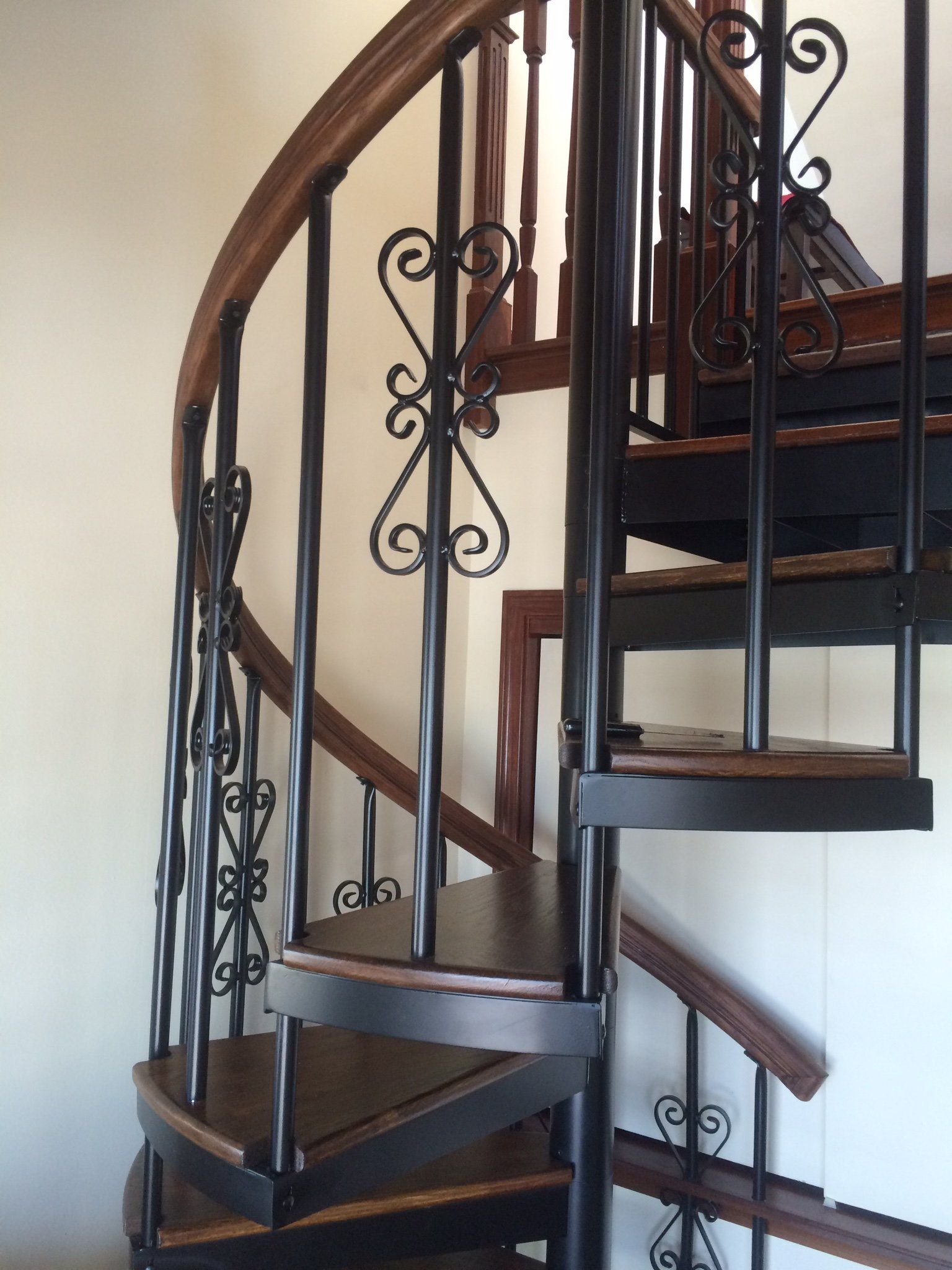 A spiral staircase with a wrought iron railing and wooden steps