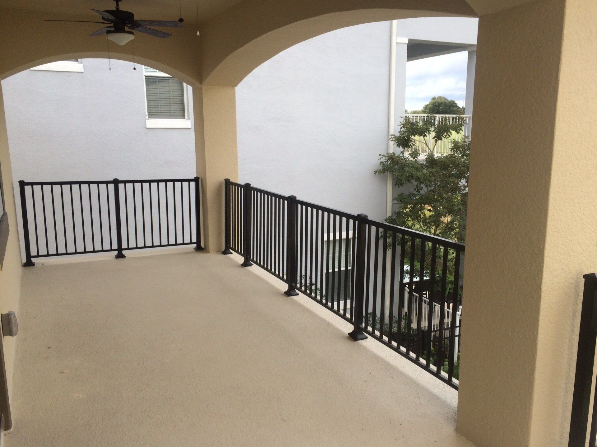 A balcony with a black railing and a ceiling fan