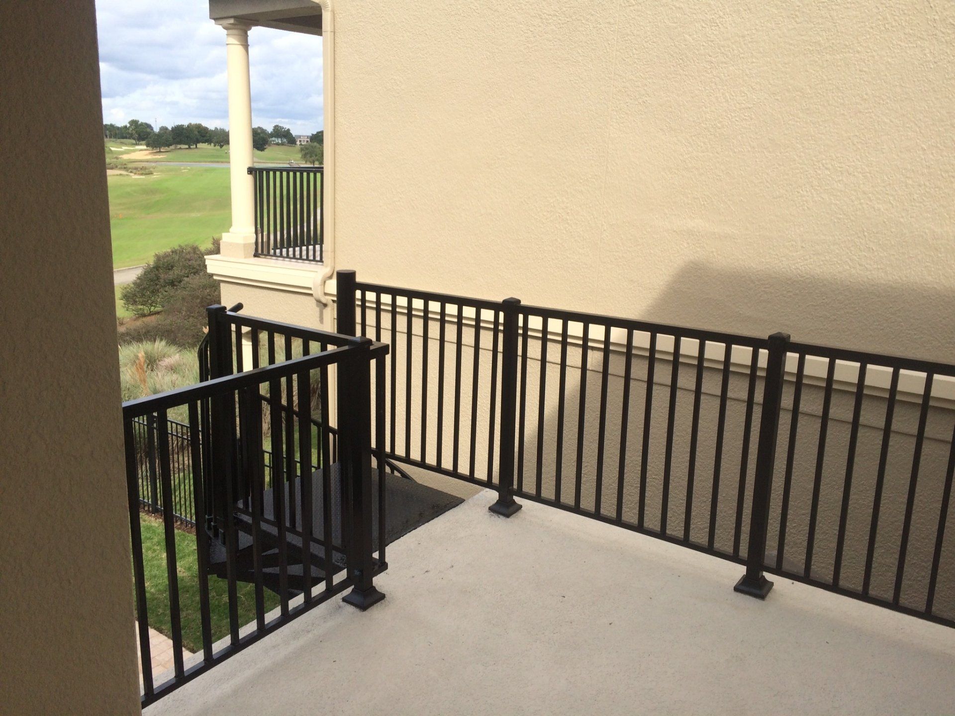 A balcony with a black railing overlooking a golf course