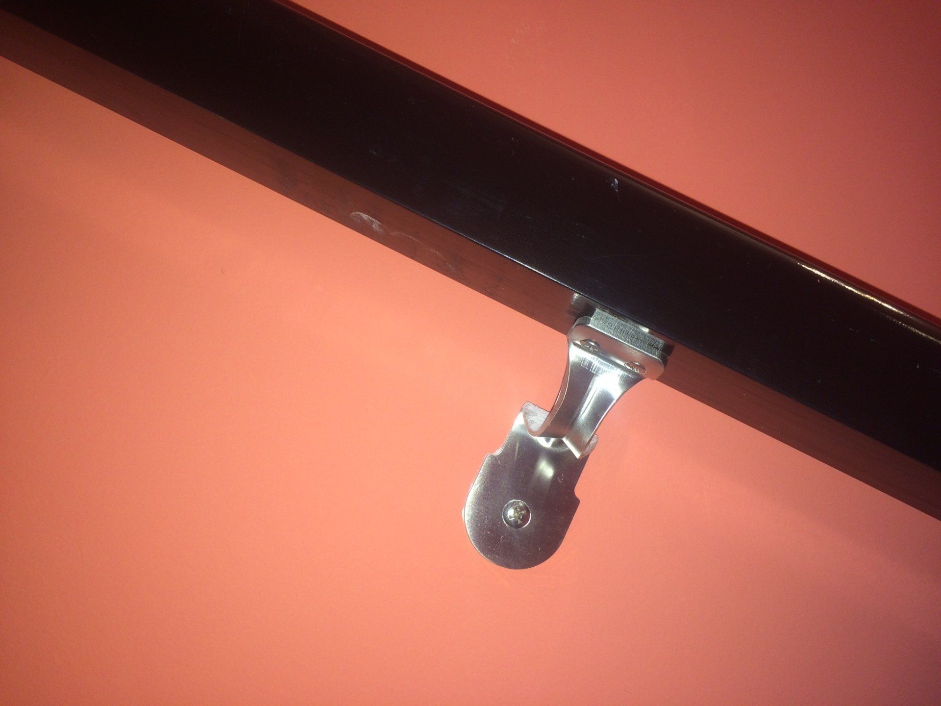 A close up of a handrail on a red wall