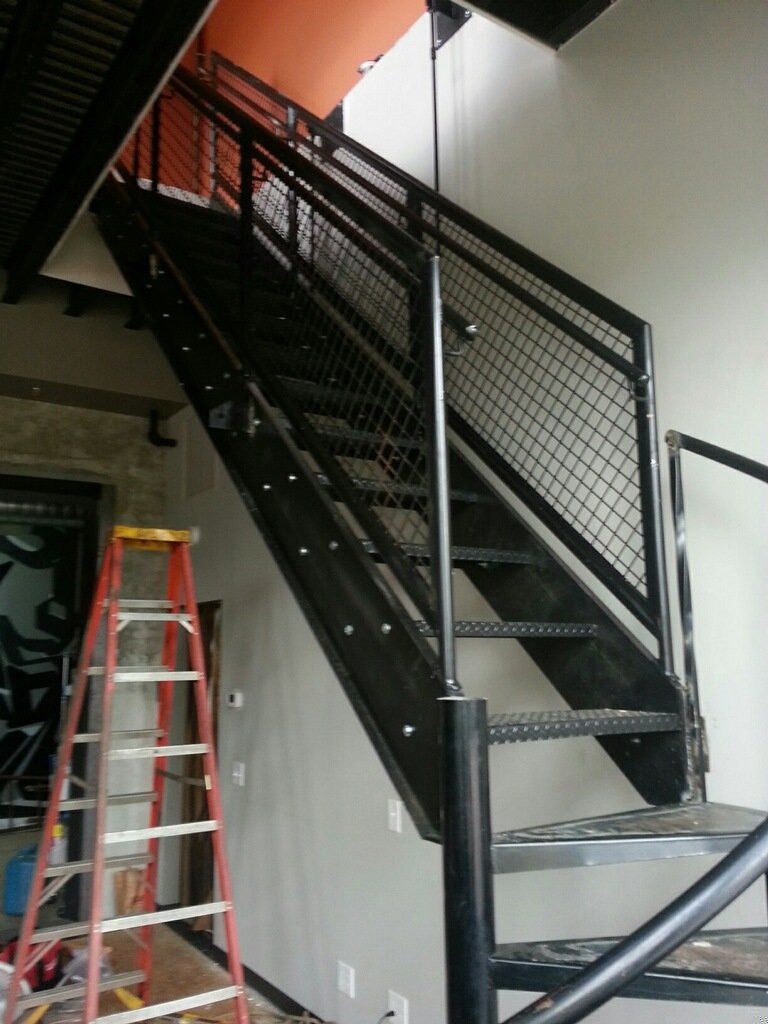 A ladder sits next to a staircase in a room