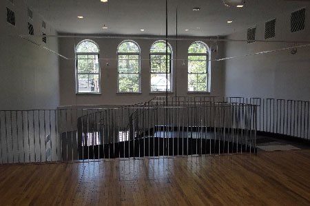 An empty room with a wooden floor and a metal railing