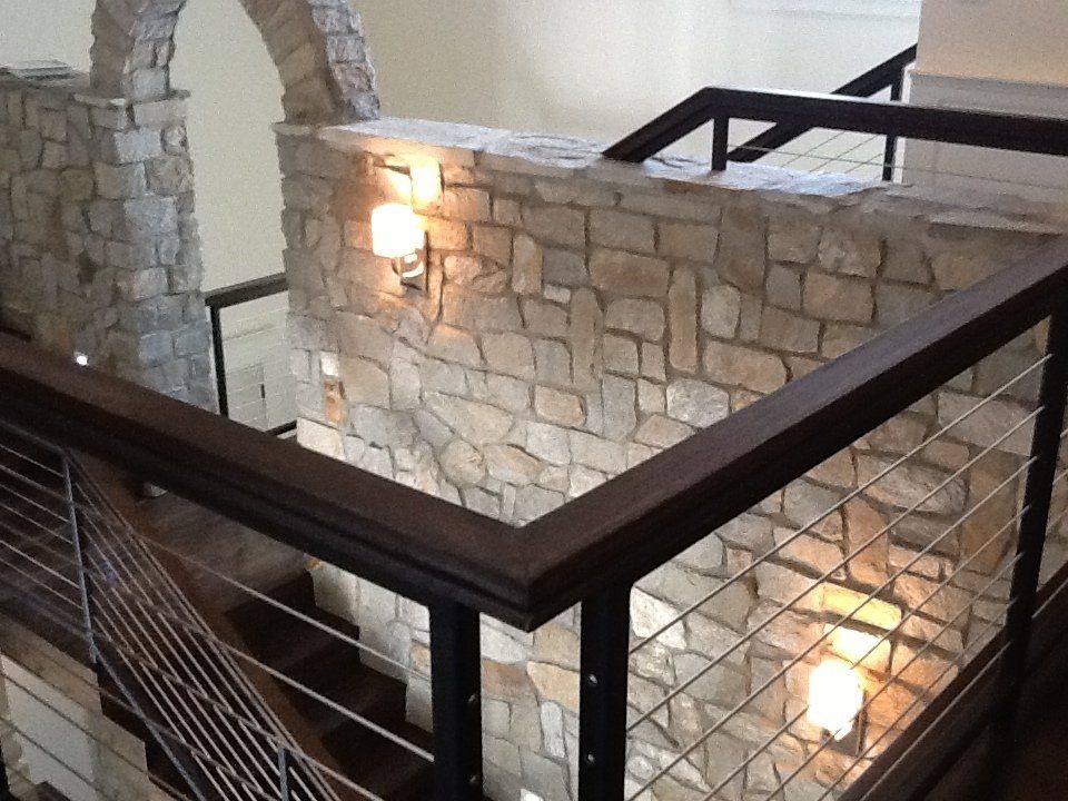 A staircase with a wooden railing and a stone wall
