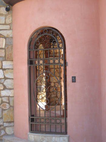A pink wall with a wrought iron gate in front of it
