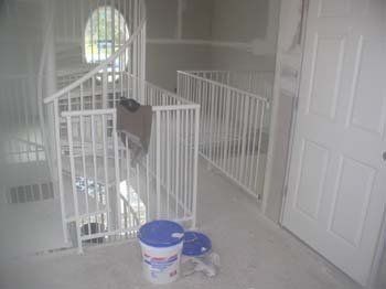 A bucket of paint is sitting on the floor next to a staircase.