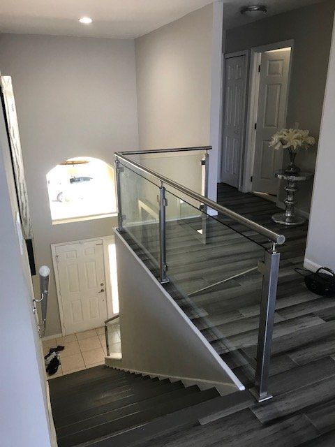 A staircase with a glass railing leading up to the second floor of a house.