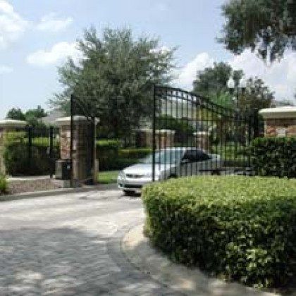 A car is parked in front of a gate in a driveway.