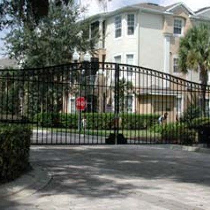A wrought iron gate leading to a house with a stop sign in front of it.