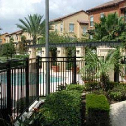 A fence surrounds a swimming pool in a residential area.