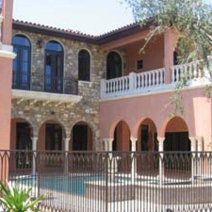A large house with arches and a pool in front of it.