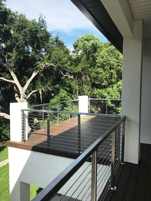 A balcony with a stainless steel railing overlooking trees