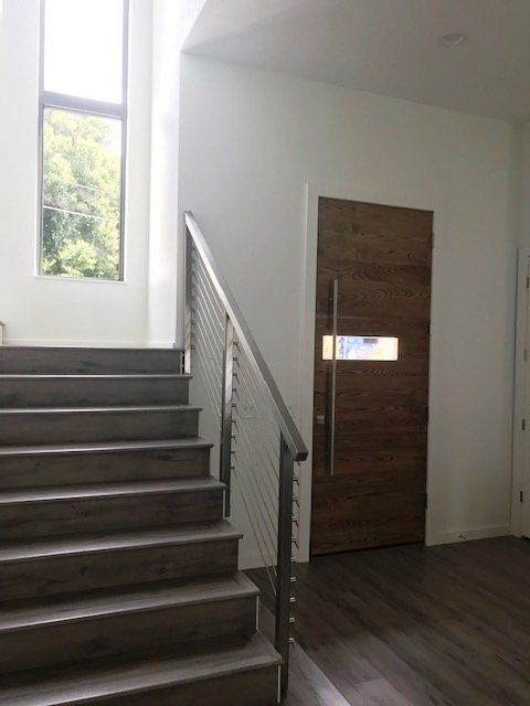 A staircase with a stainless steel railing and a wooden door