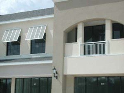 A white building with a balcony and awnings on the windows.