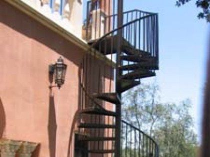 A spiral staircase is attached to the side of a building.
