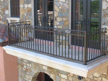 A balcony with a wrought iron railing on the side of a stone building.