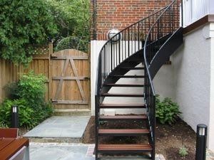 A spiral staircase is leading up to a brick wall.