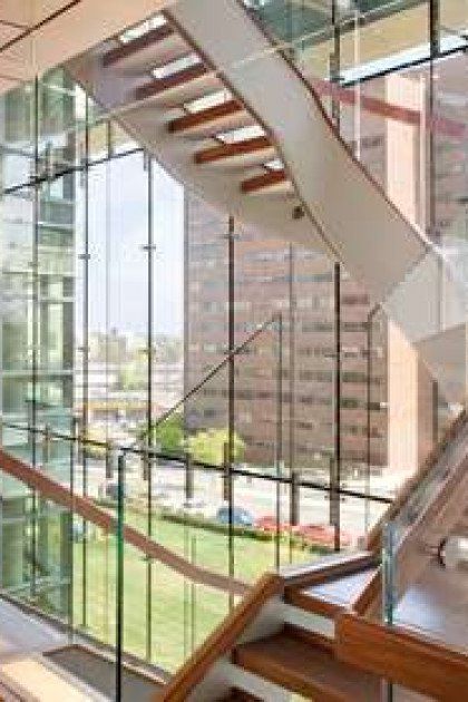 A staircase with a glass railing in a building with a lot of windows.