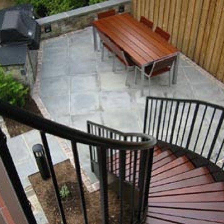 A spiral staircase leads to a patio with a table and chairs