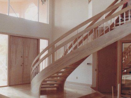 A curved wooden staircase in a large room