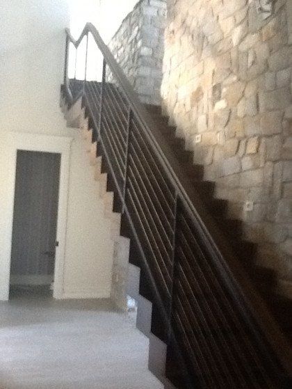 A staircase with a metal railing and a stone wall