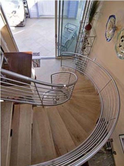 A spiral staircase with a stainless steel railing
