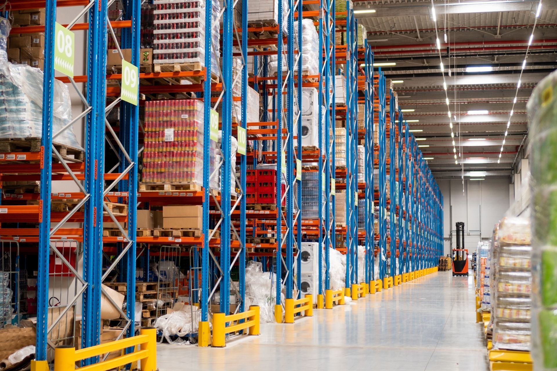 Warehouse interior with tall blue and orange shelving filled with packaged goods. — Australian Asset Compliance in Glanmire, QLD