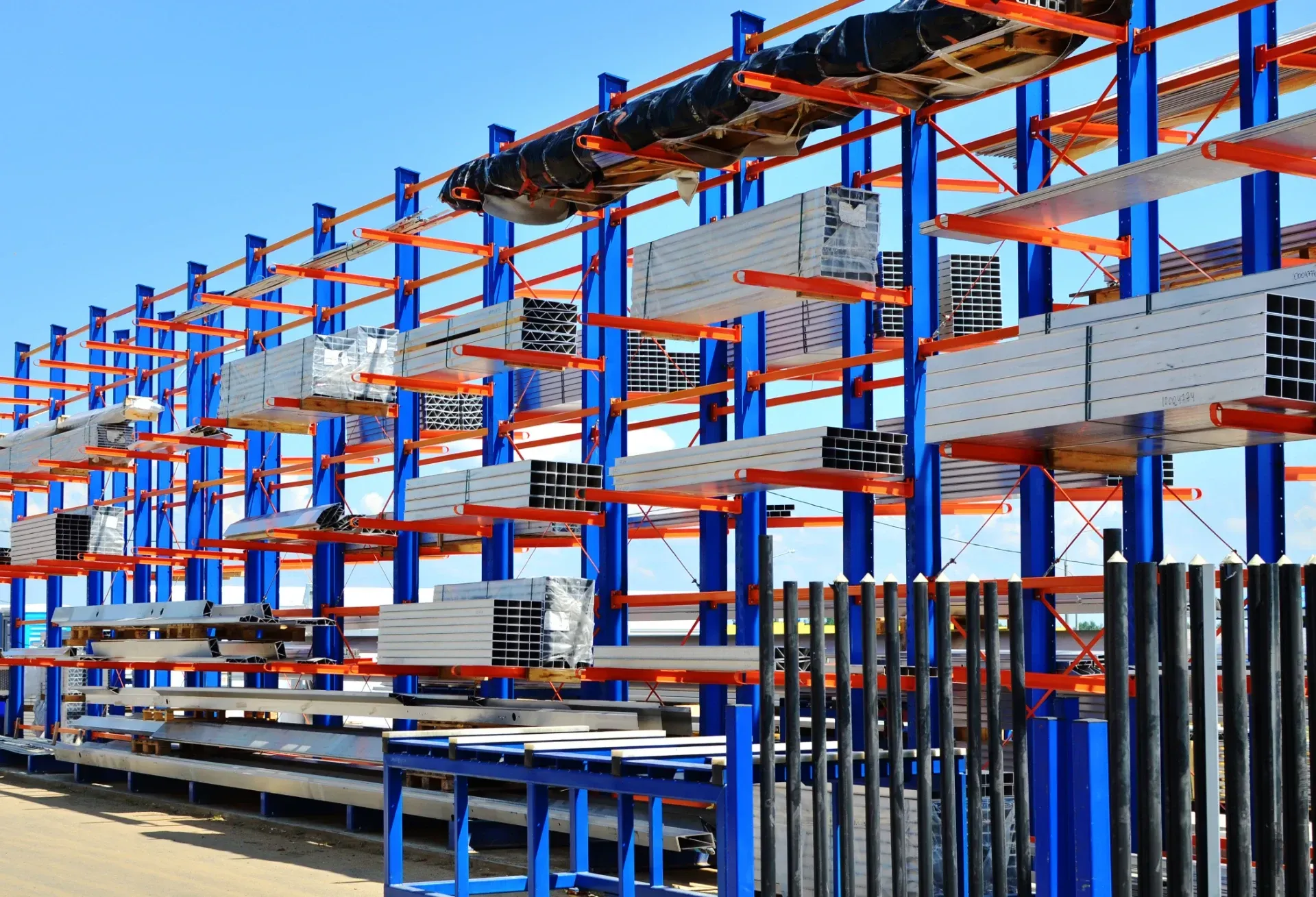 Rows of blue and orange metal shelving in an outdoor warehouse yard - pallet racking inspection Queensland