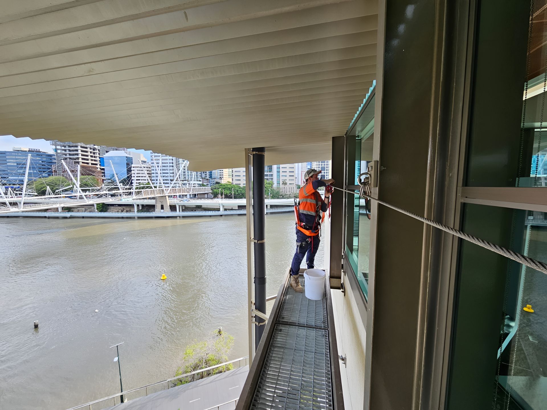 Worker on a Platform Washing Windows of a Building — Australian Asset Compliance in Emerald, QLD