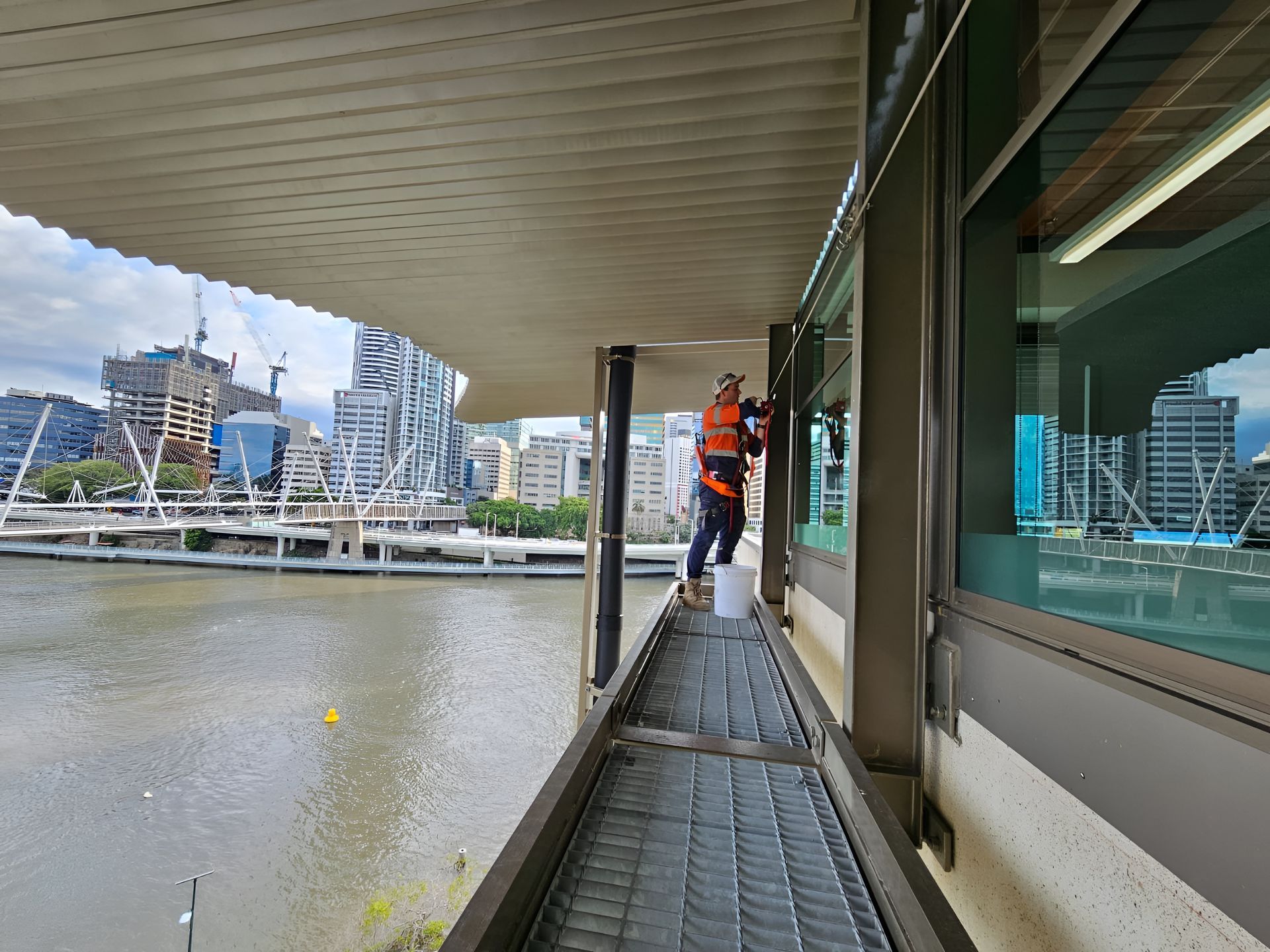 Person in Safety Harness Cleaning Windows on a Waterfront Building — Australian Asset Compliance in Glanmire, QLD