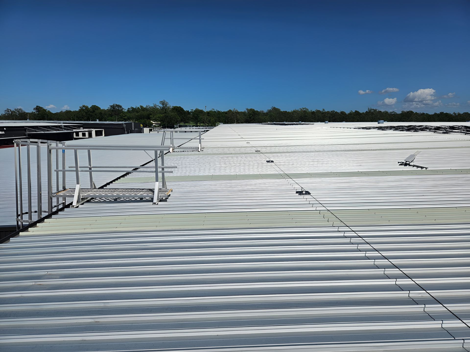 View from a metal roof on a sunny day. Safety lines and a staircase are visible. — Australian Asset Compliance in Rockhampton, QLD