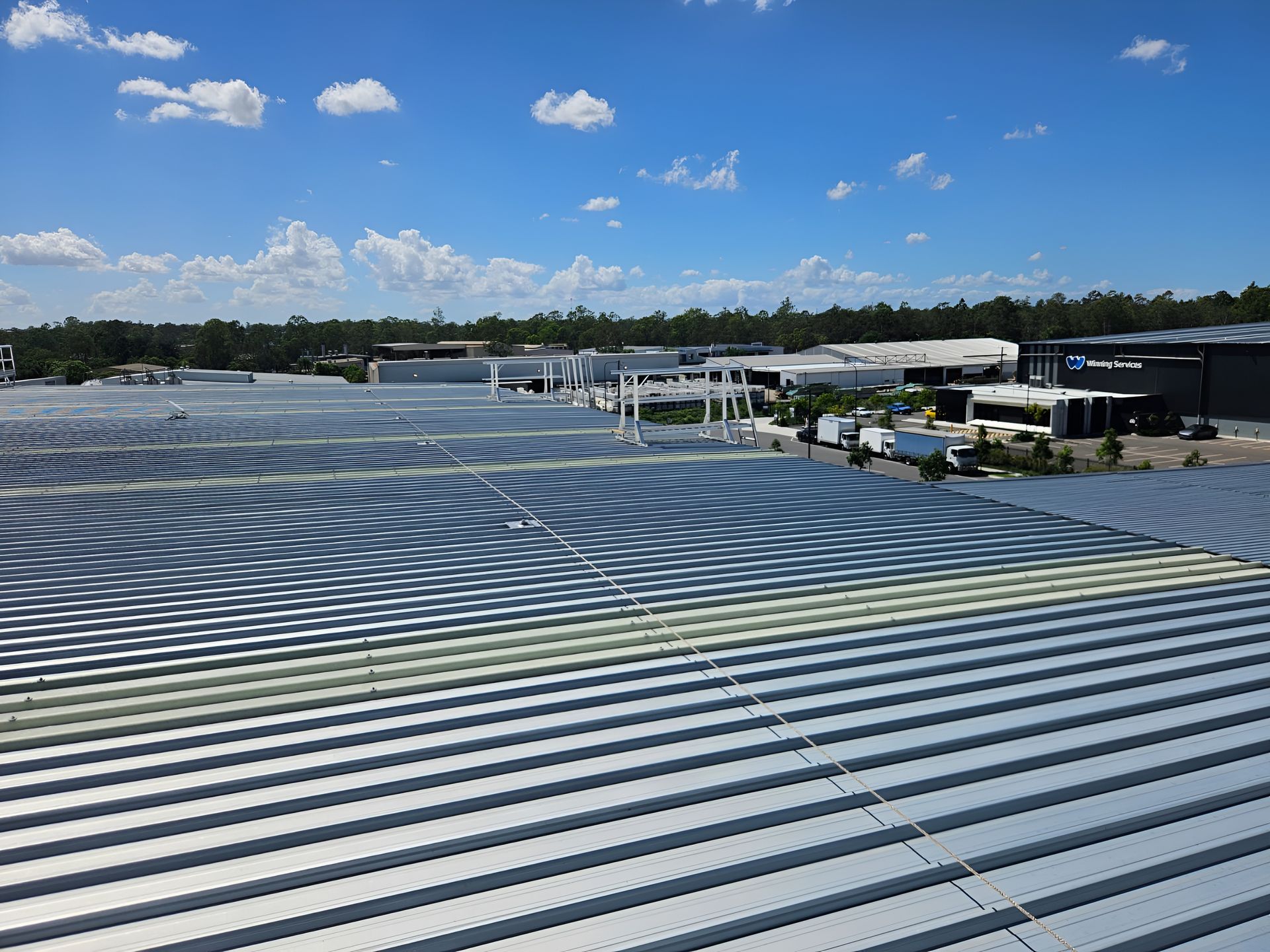 Roofer in Safety Gear on a White Corrugated Metal Roof— Australian Asset Compliance in Hunter Valley, QLD
