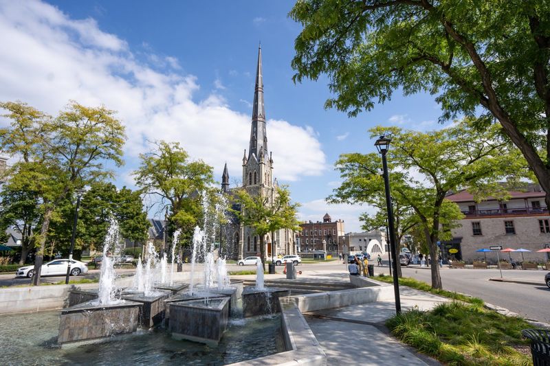 Fountain in a town square with a tall church in the background under a bright blue sky.