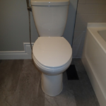White toilet in a bathroom with gray flooring and walls.