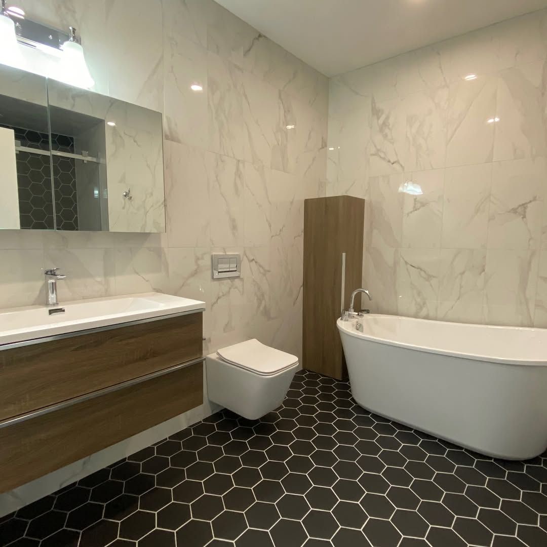 Modern bathroom with black hexagon tile floor, white walls, and a free-standing tub.