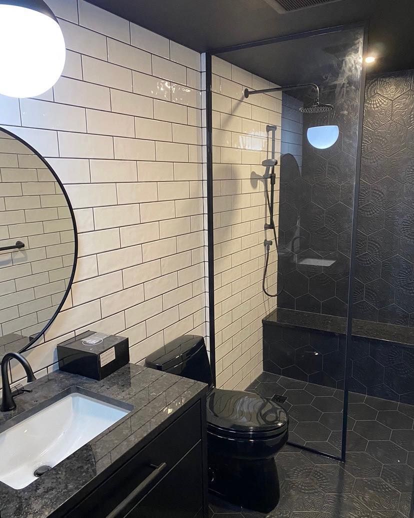 Modern bathroom with black and white tile, black fixtures, and a glass shower.