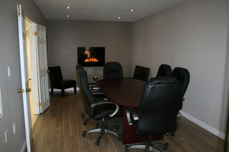 Conference room with a dark wood table and black chairs, fireplace on the wall.