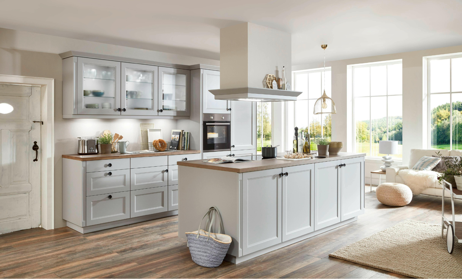 Light gray kitchen with island and wooden countertops, near a window.