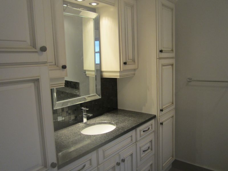 Bathroom with white cabinets, a dark countertop, and a mirror over the sink.
