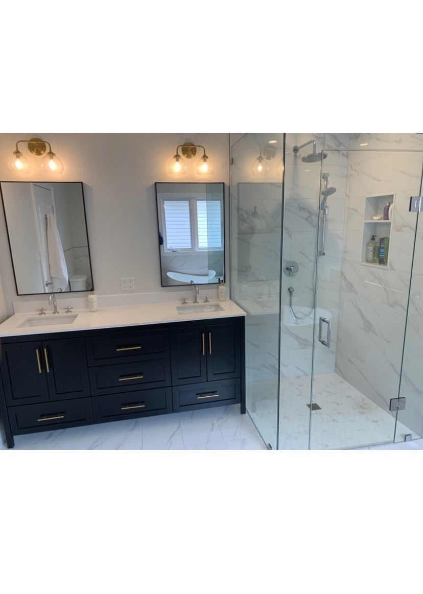 Bathroom with double vanity, large shower, and gold hardware.