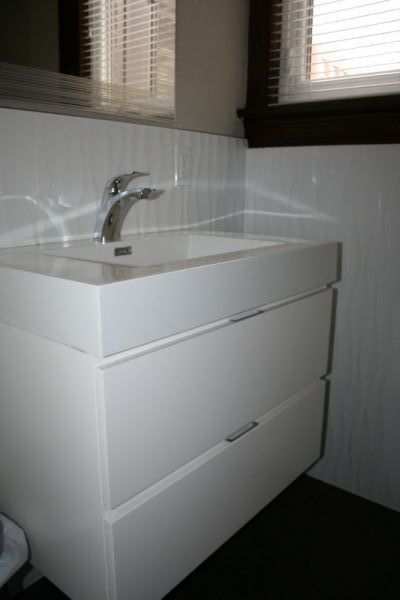 White bathroom vanity with a sink and two drawers; a window is behind it.